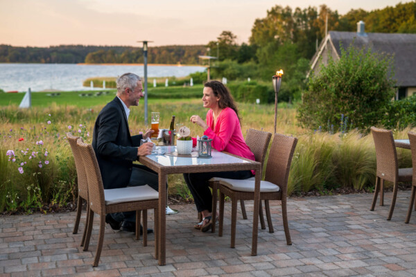 Ein Paar beim Abendessen auf einer Terrasse mit Seeblick