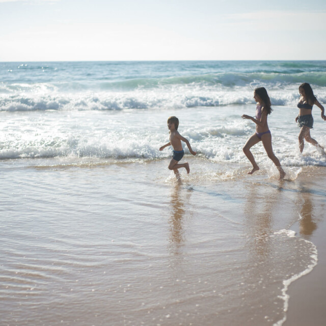 Drei Kinder laufen am Strand