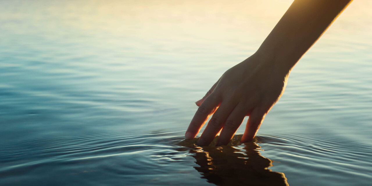 Hand gleitet durch das Wasser