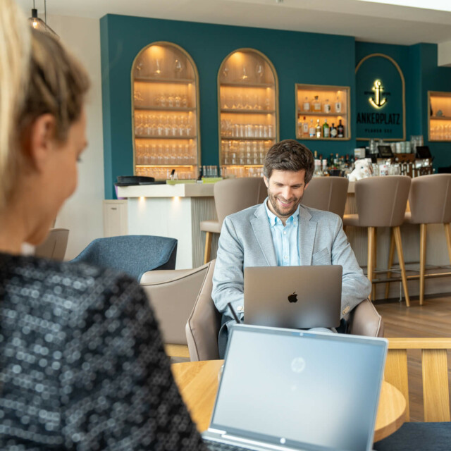 Zwei Menschen sitzen am Laptop in einer Bar