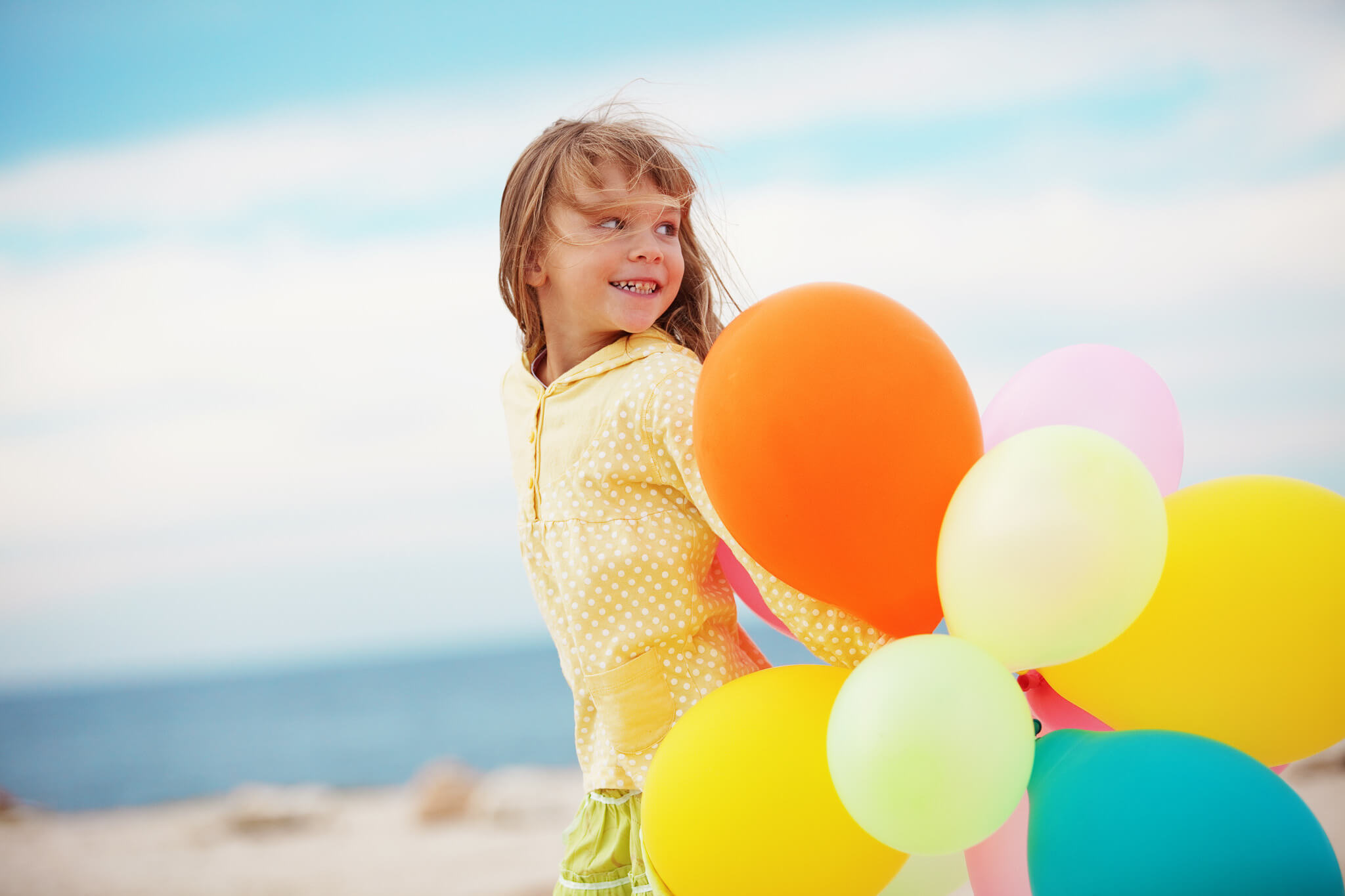 Ein junges Mädchen am Strand mit Luftballons