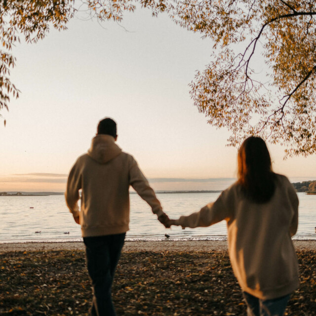 Paar geht händchenhaltend auf einen See zu